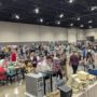 Large crowd at Vintage Computer Festival Midwest browsing exhibits, vendor tables, and retro computer setups.