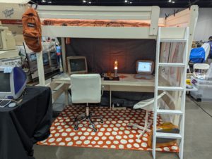 Retro bedroom display at Vintage Computer Festival Midwest with two Apple iMac G3 computers, lava lamp, loft bed, and polka-dot rug.
